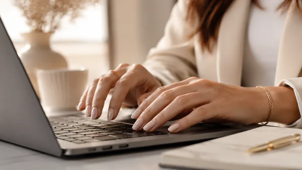 Femme travaillant et tapant au clavier d'ordinateur avec une manucure press-on nails courte, prouvant le confort au quotidien.
