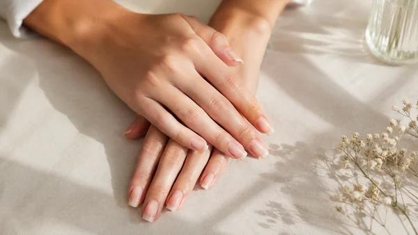 Mains de femme avec des ongles naturels sains en pleine croissance.