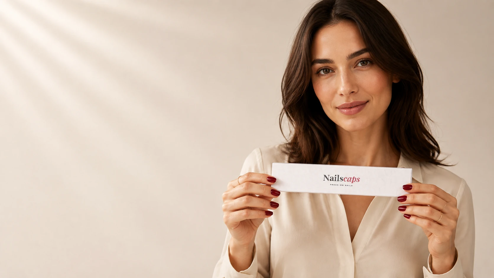 Main portant un press-on nails Nailscaps, à côté du coffret